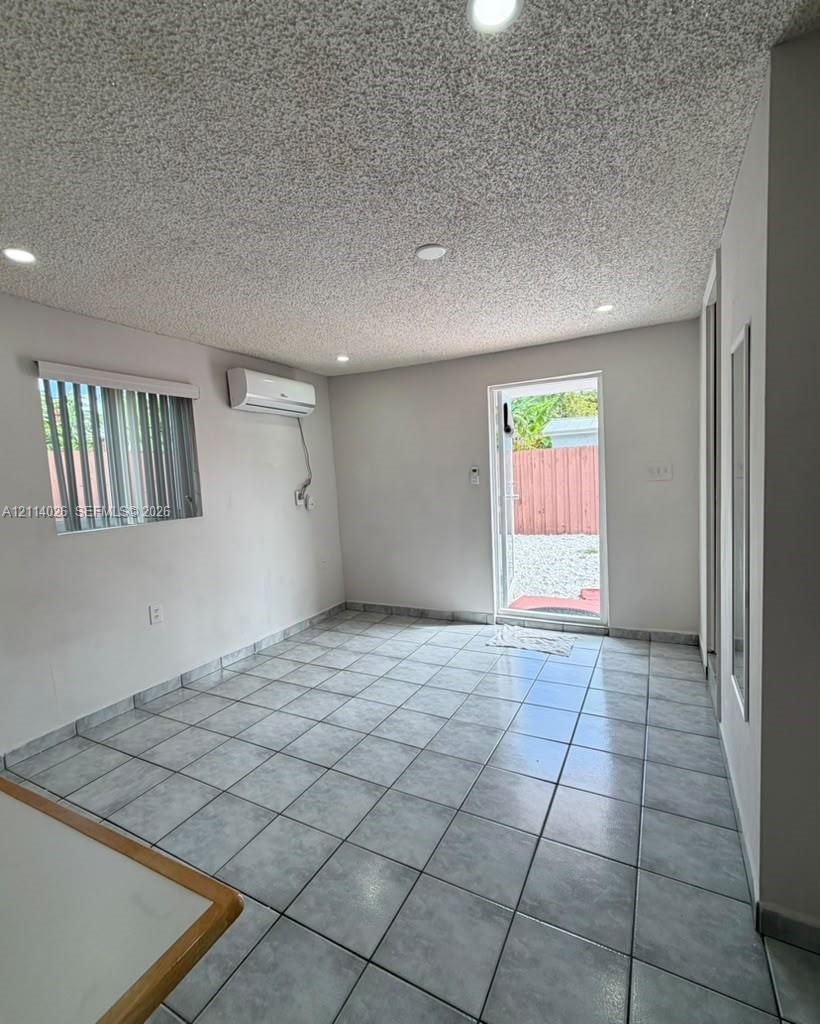 Interior space featuring ceramic tile flooring, recessed lighting, wall-mounted air conditioning unit, and a glass-paneled exterior door