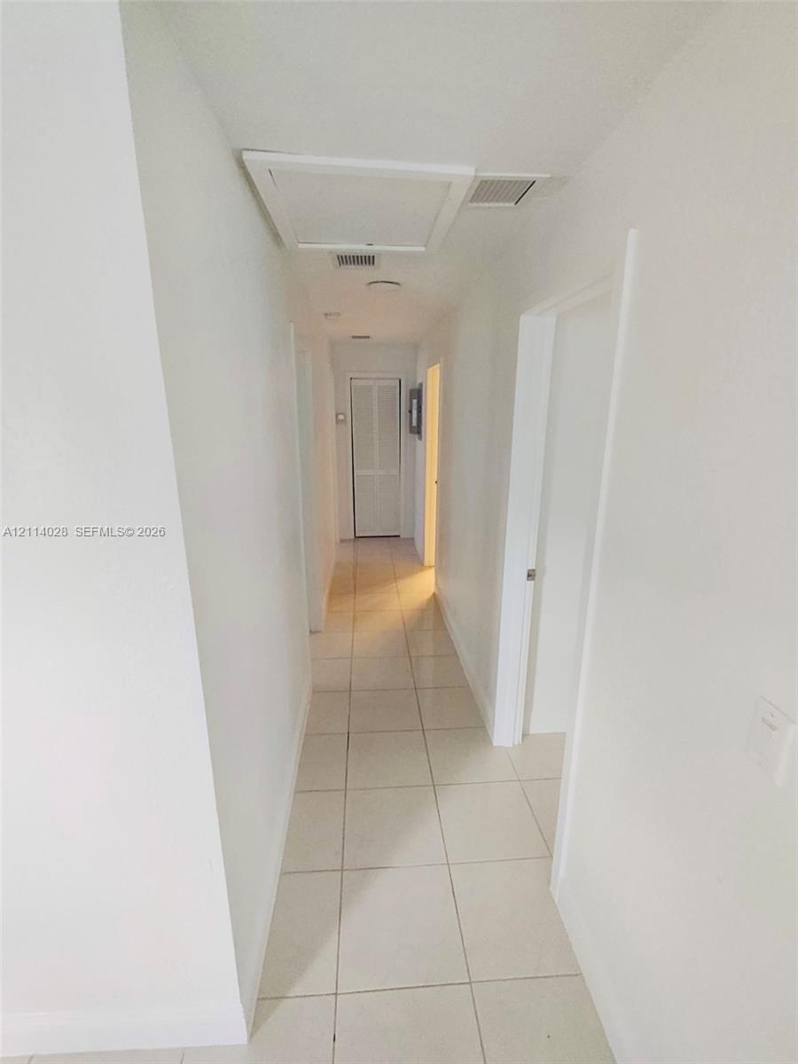 Hallway featuring large-format ceramic tile flooring, neutral wall finishes, recessed lighting, and louvered closet doors Hallway featuring large-format ceramic tile flooring, neutral wall finishes, recessed lighting, and louvered closet doors