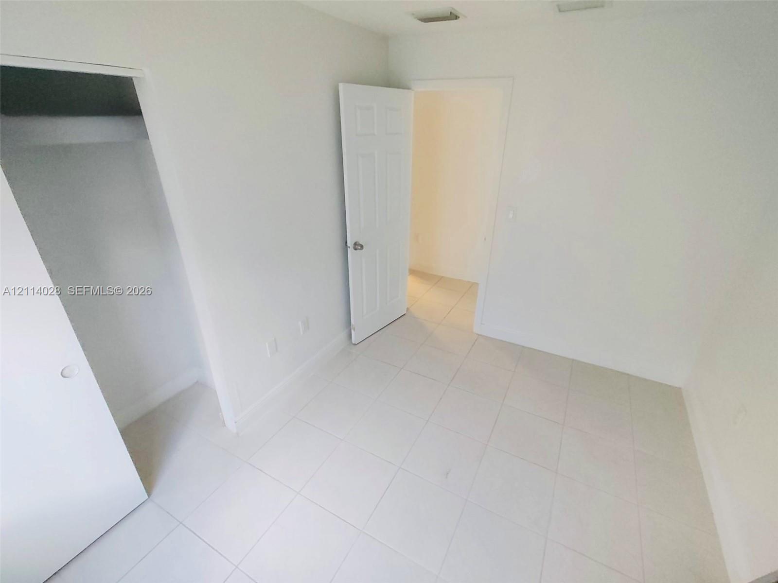 Interior room featuring neutral ceramic tile flooring, six-panel doors, and a built-in closet with a shelf Interior room featuring neutral ceramic tile flooring, six-panel doors, and a built-in closet with a shelf
