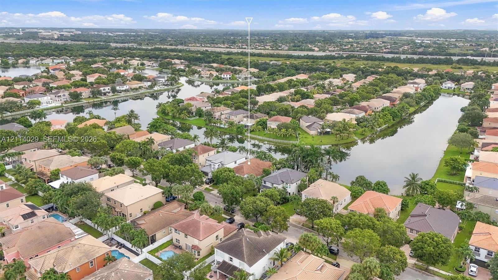 Aerial perspective featuring a residential property situated on a waterway with mature trees and a tile roof