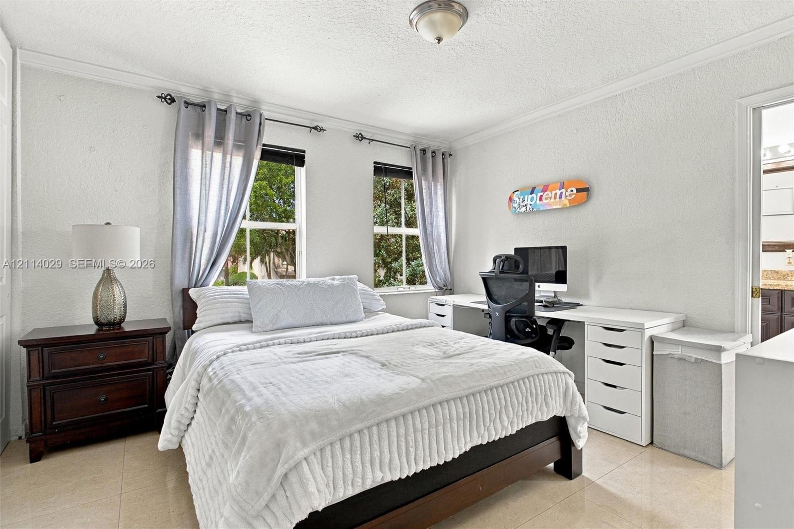 Room featuring neutral tile flooring, crown molding, and dual windows with consistent natural lighting