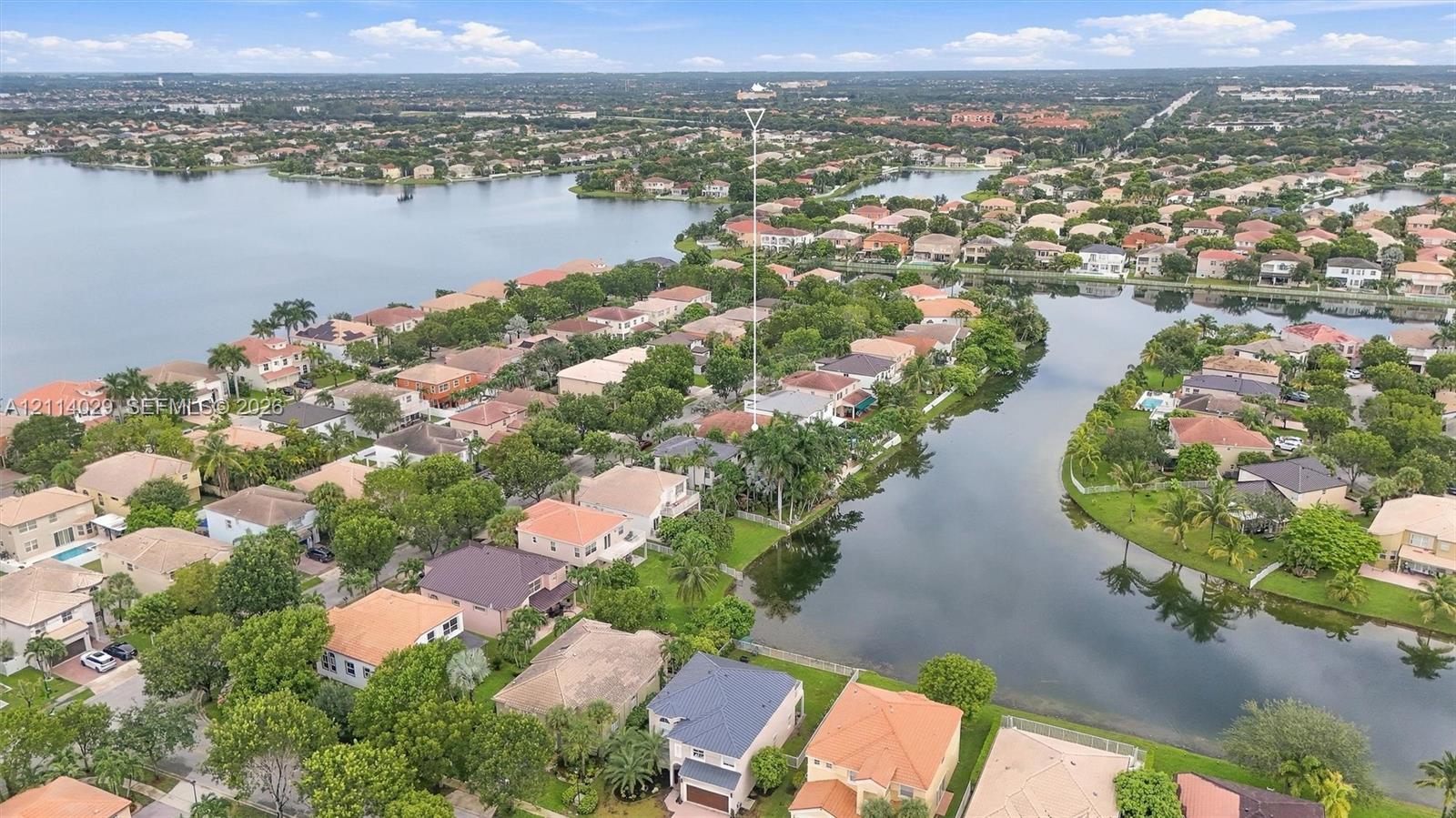 Aerial perspective of a waterfront residential property featuring an expansive canal system, mature landscaping, and multi-story residences