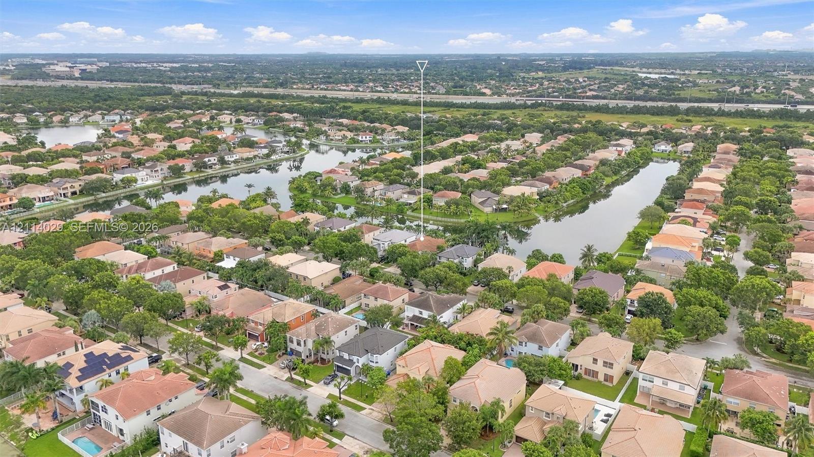Aerial perspective of residential community featuring winding waterfront canals, mature trees, and interconnected paved thoroughfares