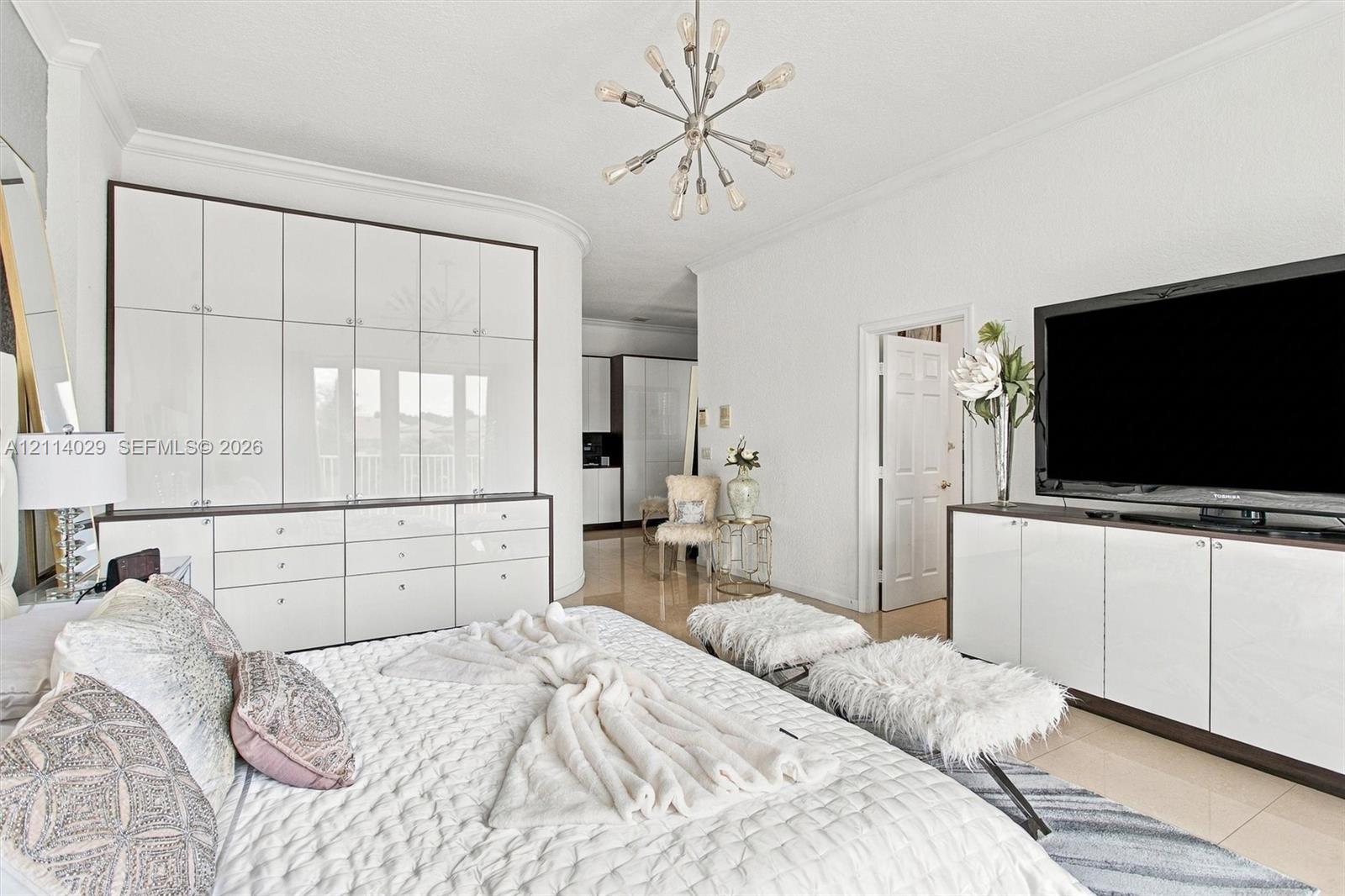 Floor-to-ceiling built-in white cabinetry, polished stone flooring, custom integrated media console, and a contemporary multi-arm sputnik chandelier