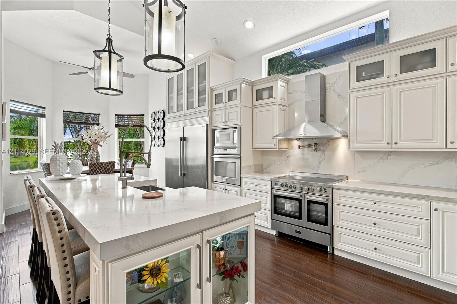 Kitchen featuring white cabinetry with glass-front uppers, solid surface countertops, a professional-grade stainless steel range with matching vent hood, and wood-finish flooring