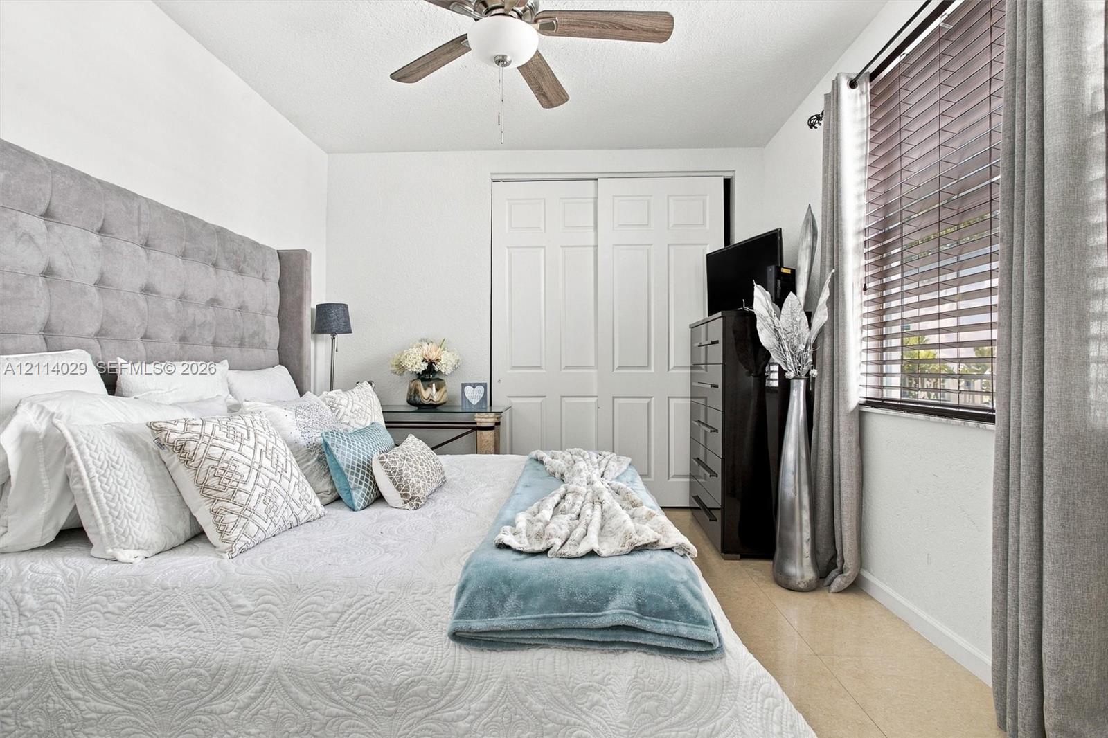 Room featuring a ceiling fan with integrated lighting, dual-panel closet doors, and wood-finish flooring