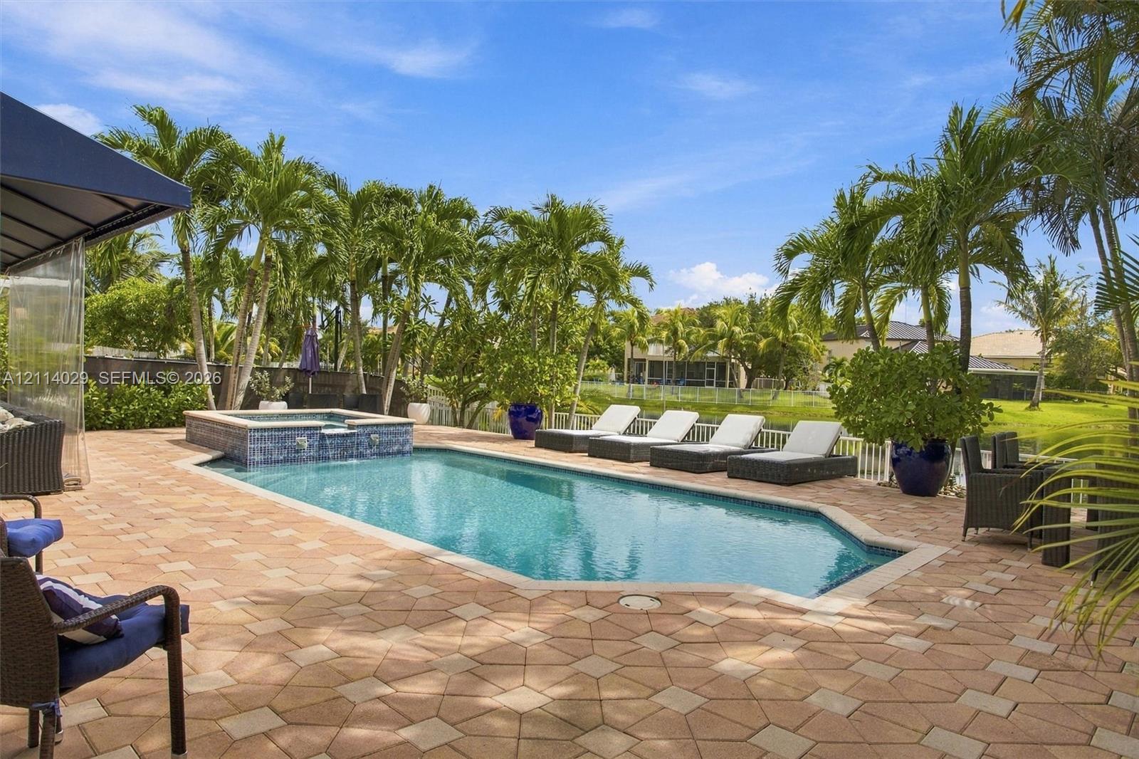 Custom-designed swimming pool with an integrated elevated spa, finished with decorative tile accents and surrounded by expansive paver decking