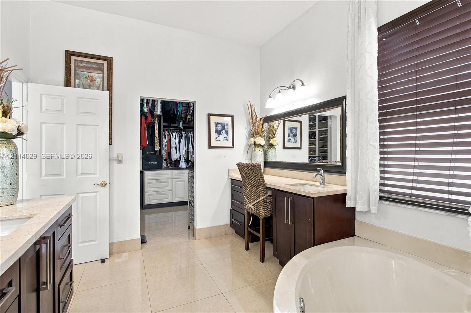Bathroom featuring dark wood-finish cabinetry, a built-in vanity station, a soaking tub, and a reach-in closet with integrated storage