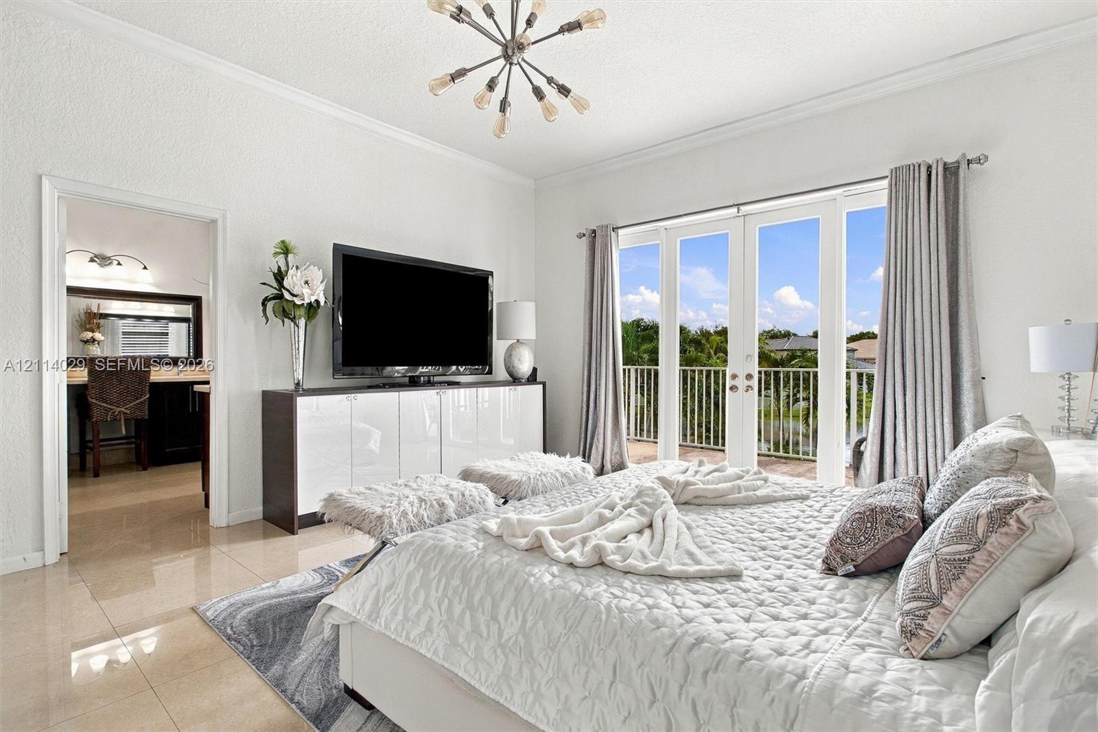 Polished tile flooring, modern sputnik-style chandelier, and double French doors opening to a railed balcony