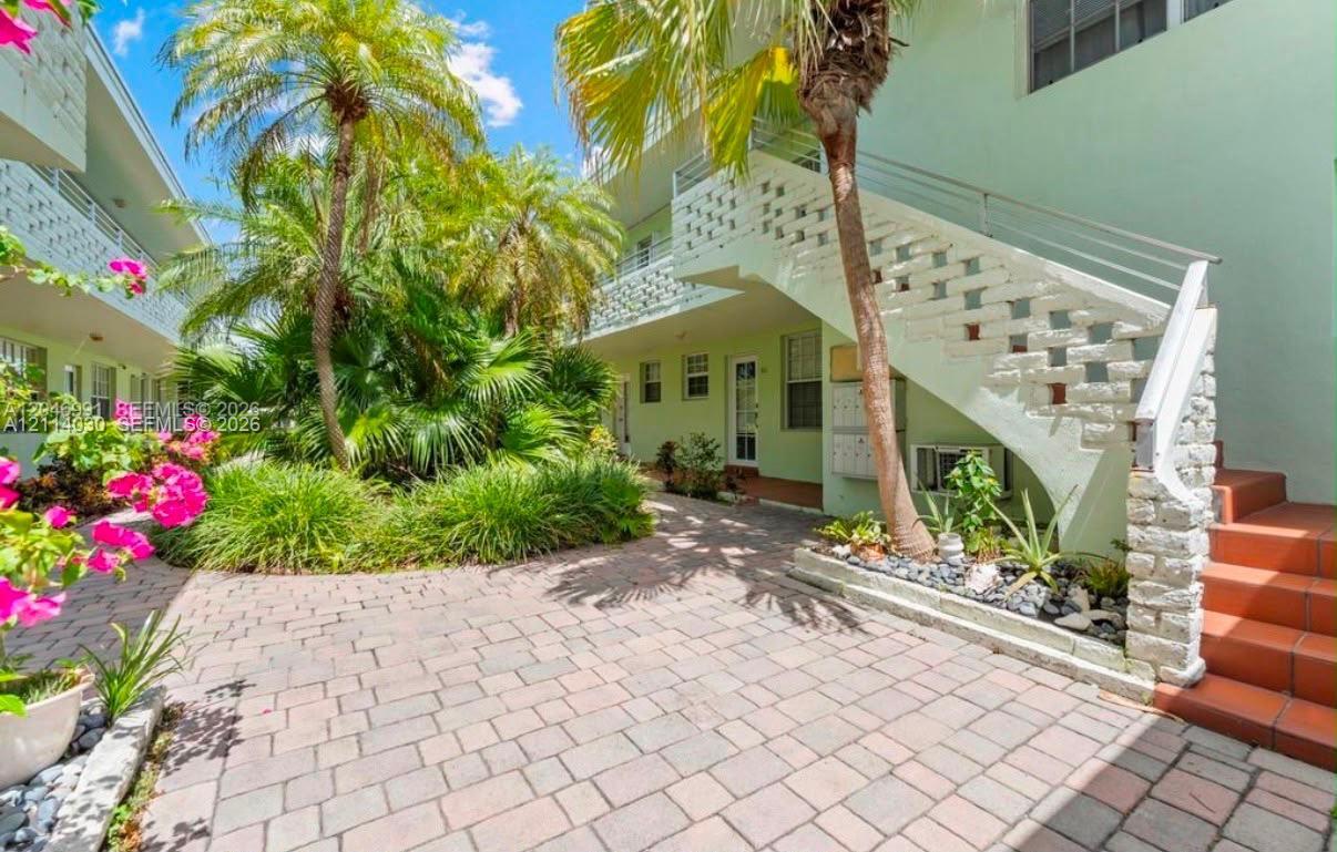 Exterior courtyard featuring stone paver flooring, open-air staircases with decorative masonry accents, and mature palm landscaping