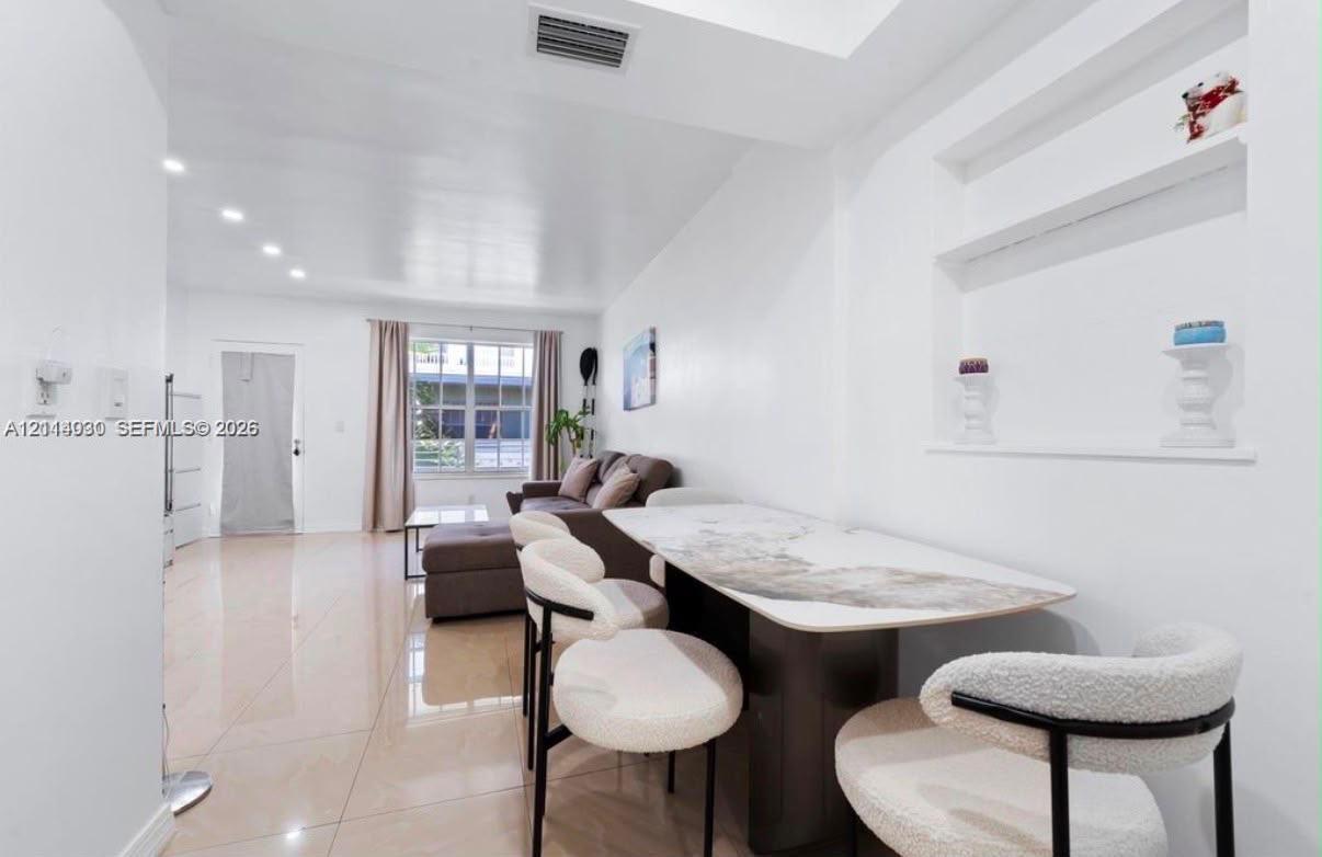 Open-concept interior featuring high-gloss tile flooring, recessed ceiling lighting, and a built-in recessed wall niche