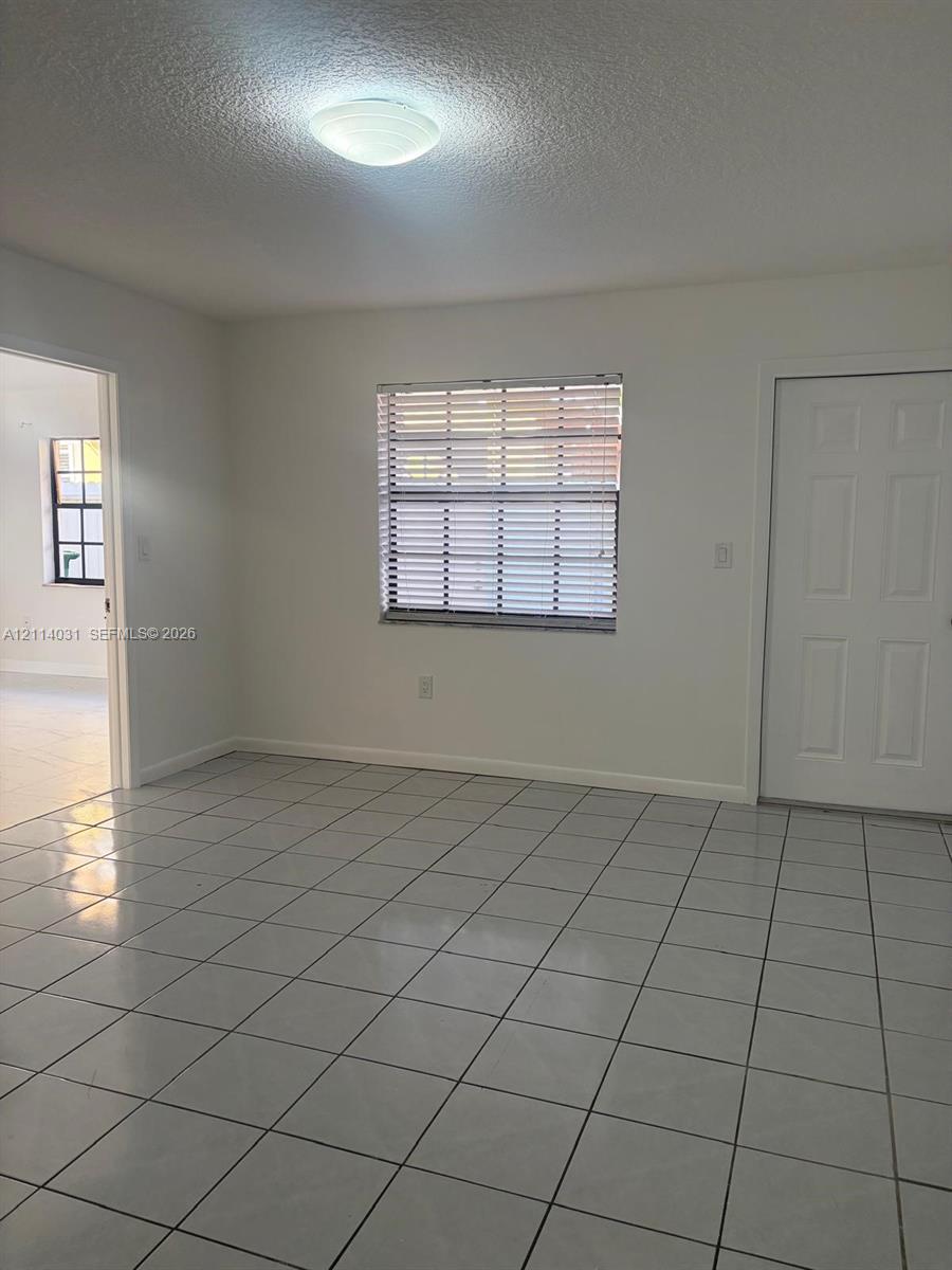 Ceramic tile flooring, neutral wall finishes, flush-mount ceiling lighting, and a six-panel interior door Ceramic tile flooring, neutral wall finishes, flush-mount ceiling lighting, and a six-panel interior door