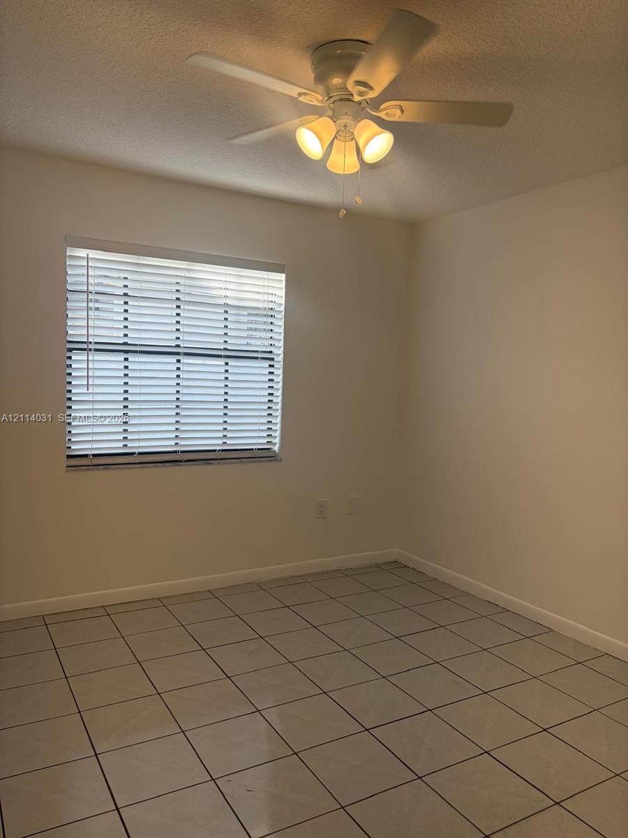 Interior space featuring neutral wall paint, tile flooring, a window with installed horizontal blinds, and a ceiling fan with integrated lighting Interior space featuring neutral wall paint, tile flooring, a window with installed horizontal blinds, and a ceiling fan with integrated lighting