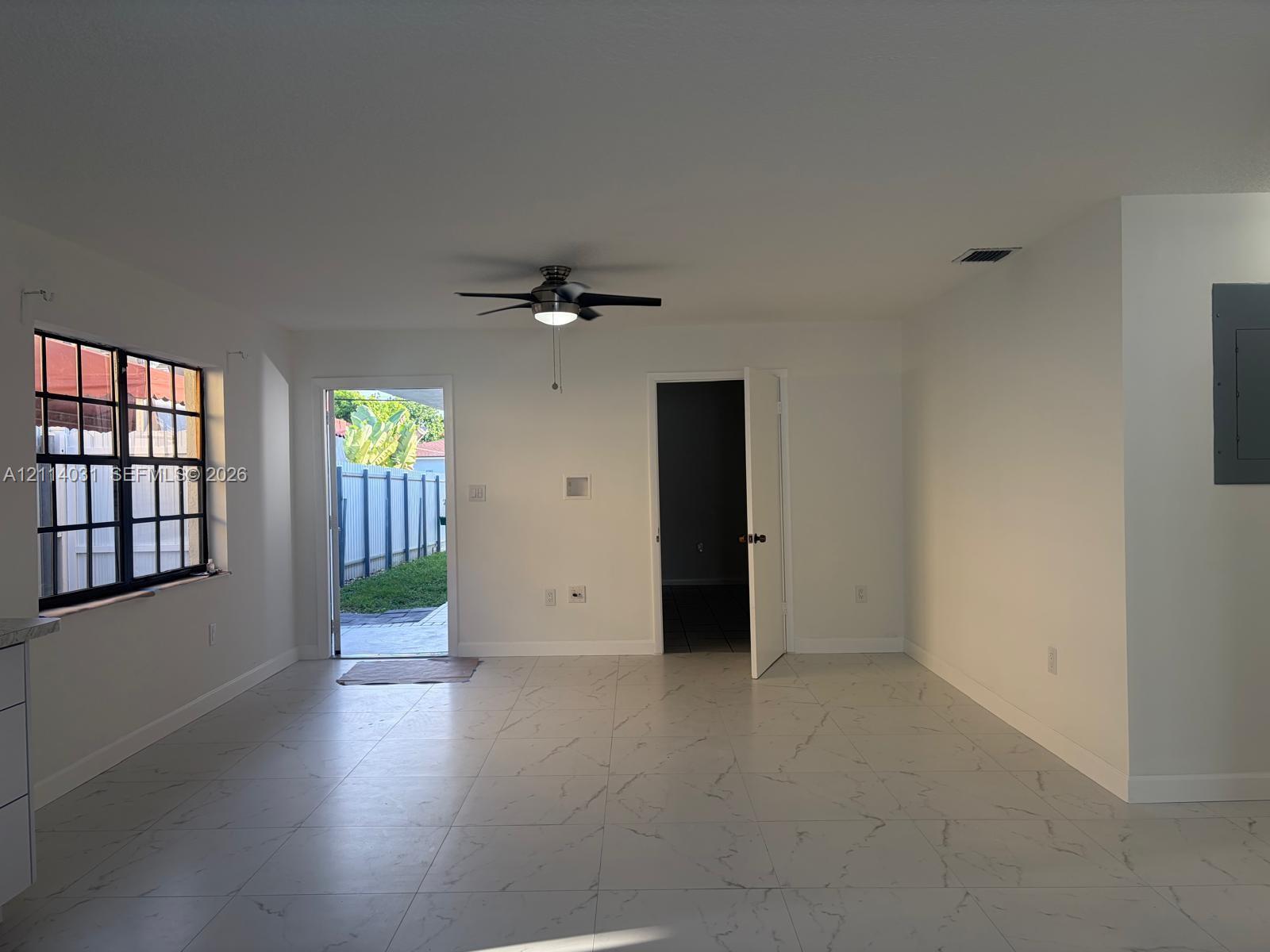 Large-format tile flooring, multi-pane window, ceiling fan with integrated lighting, and exterior access door Large-format tile flooring, multi-pane window, ceiling fan with integrated lighting, and exterior access door