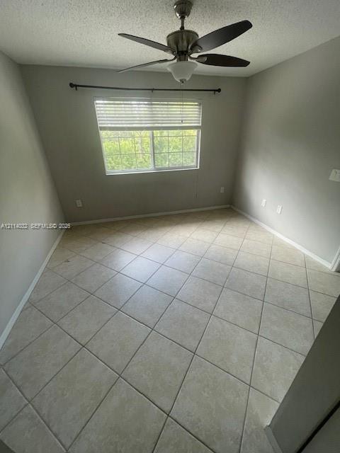 Neutral-toned interior space featuring diagonal tile flooring, a multi-blade ceiling fan with integrated lighting, and a window with horizontal blinds and a decorative curtain rod