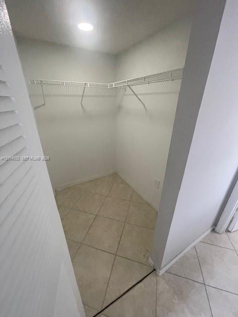 Walk-in closet featuring ceramic tile flooring, L-shaped wire shelving, and recessed lighting