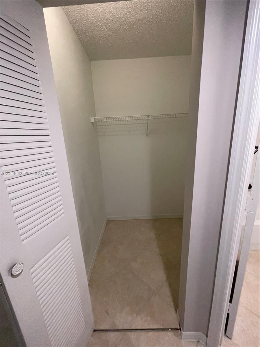 Storage closet featuring louvered bi-fold doors, tile flooring, and integrated wire shelving