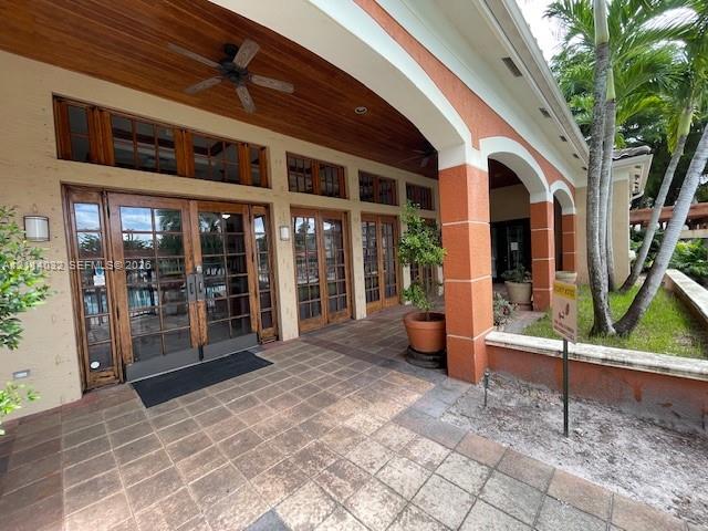 Covered lanai featuring a wood-paneled ceiling, recessed lighting, tile flooring, arched structural pillars, and multi-pane glass doors with wood framing