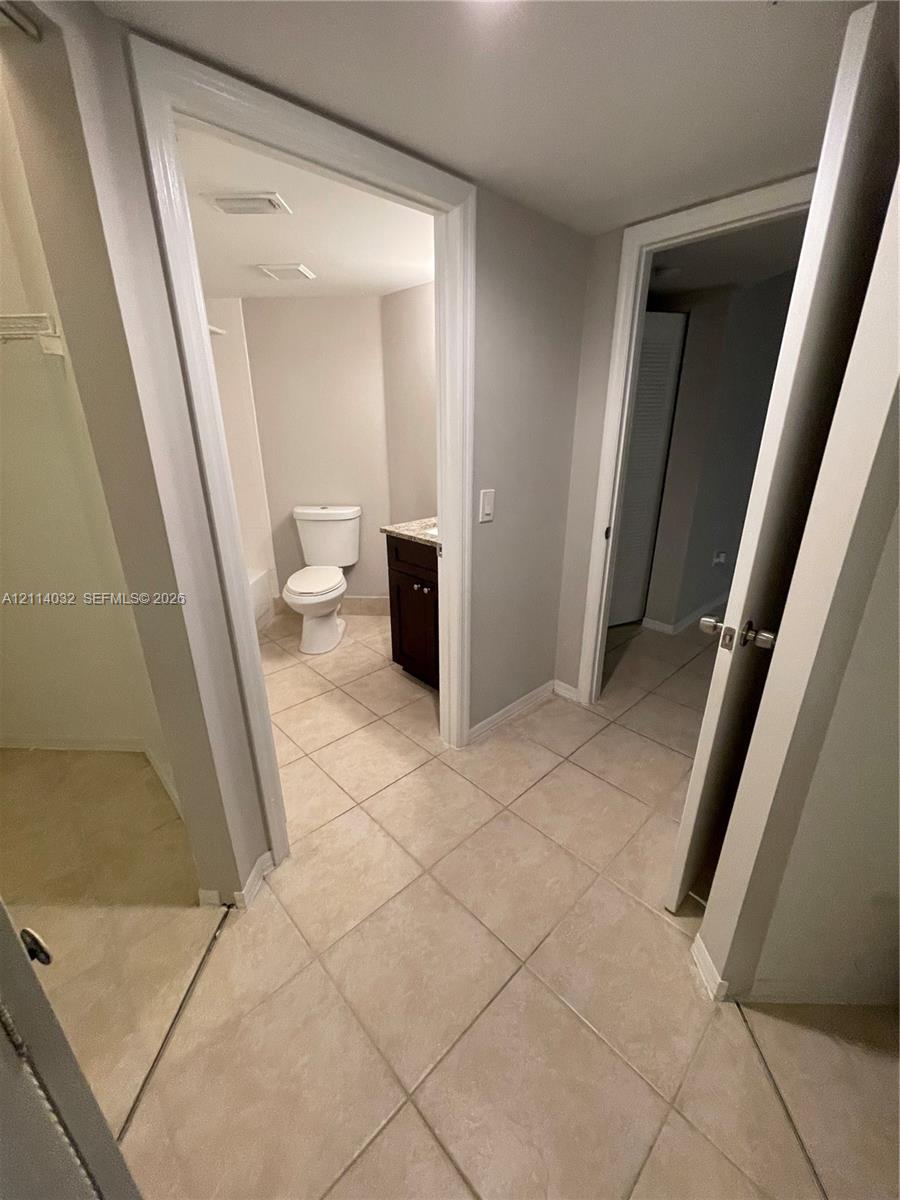 Ceramic tile flooring, vanity with stone-finish countertop, and neutral wall tones