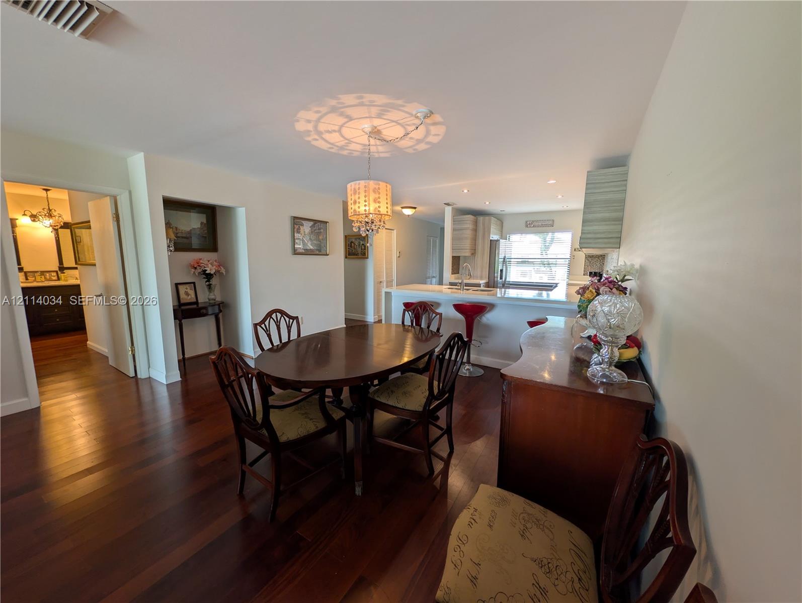 Dining area featuring wood-finish flooring, a decorative crystal-style chandelier, and a breakfast bar with stone-finish countertops