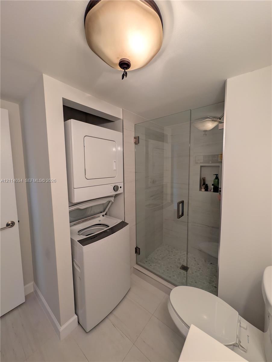 Walk-in shower featuring a glass enclosure, pebble-stone flooring, and a tiled wall niche, paired with a recessed laundry closet and overhead dome lighting