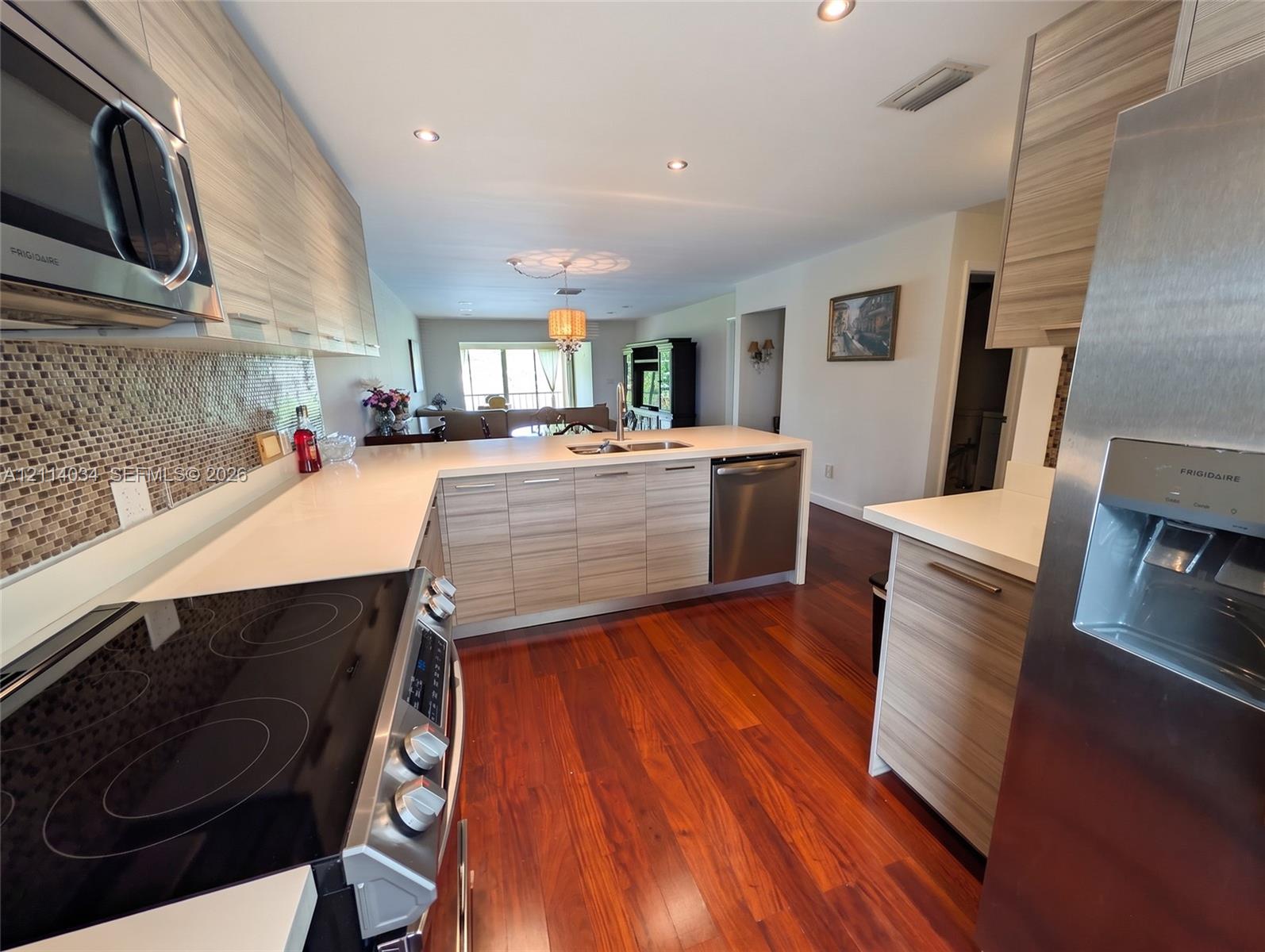 Kitchen featuring horizontal-grain wood cabinetry, quartz countertops, stainless steel appliances, mosaic tile backsplash, and wood-finish flooring