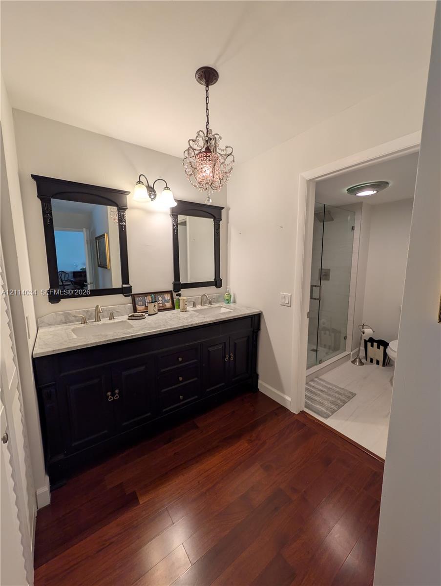 Double vanity featuring a dark-finish wood cabinet, stone-surface countertop, dual drop-in sinks, and a decorative crystal-style pendant fixture