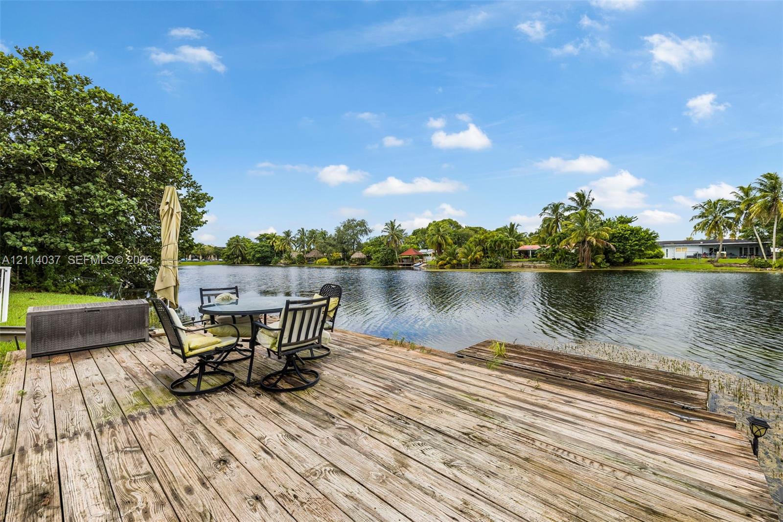 Waterfront wooden deck featuring plank decking, direct water access, and mature landscaping