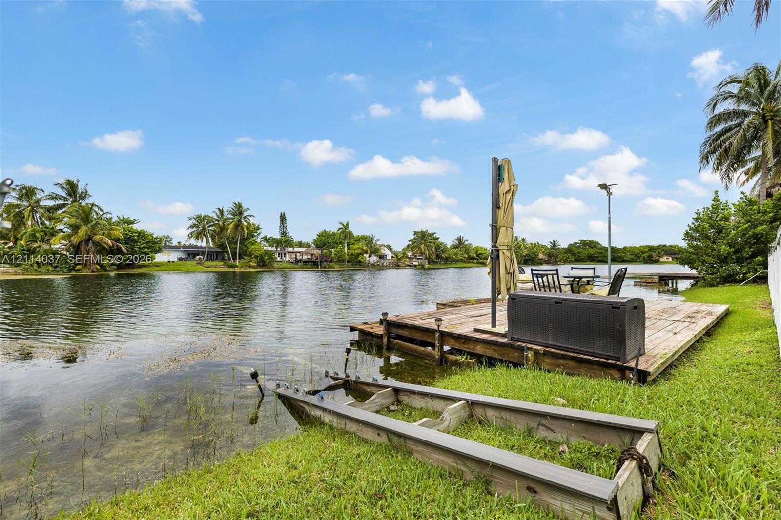 Waterfront property featuring a wood-plank dock, canal access, and expansive green space