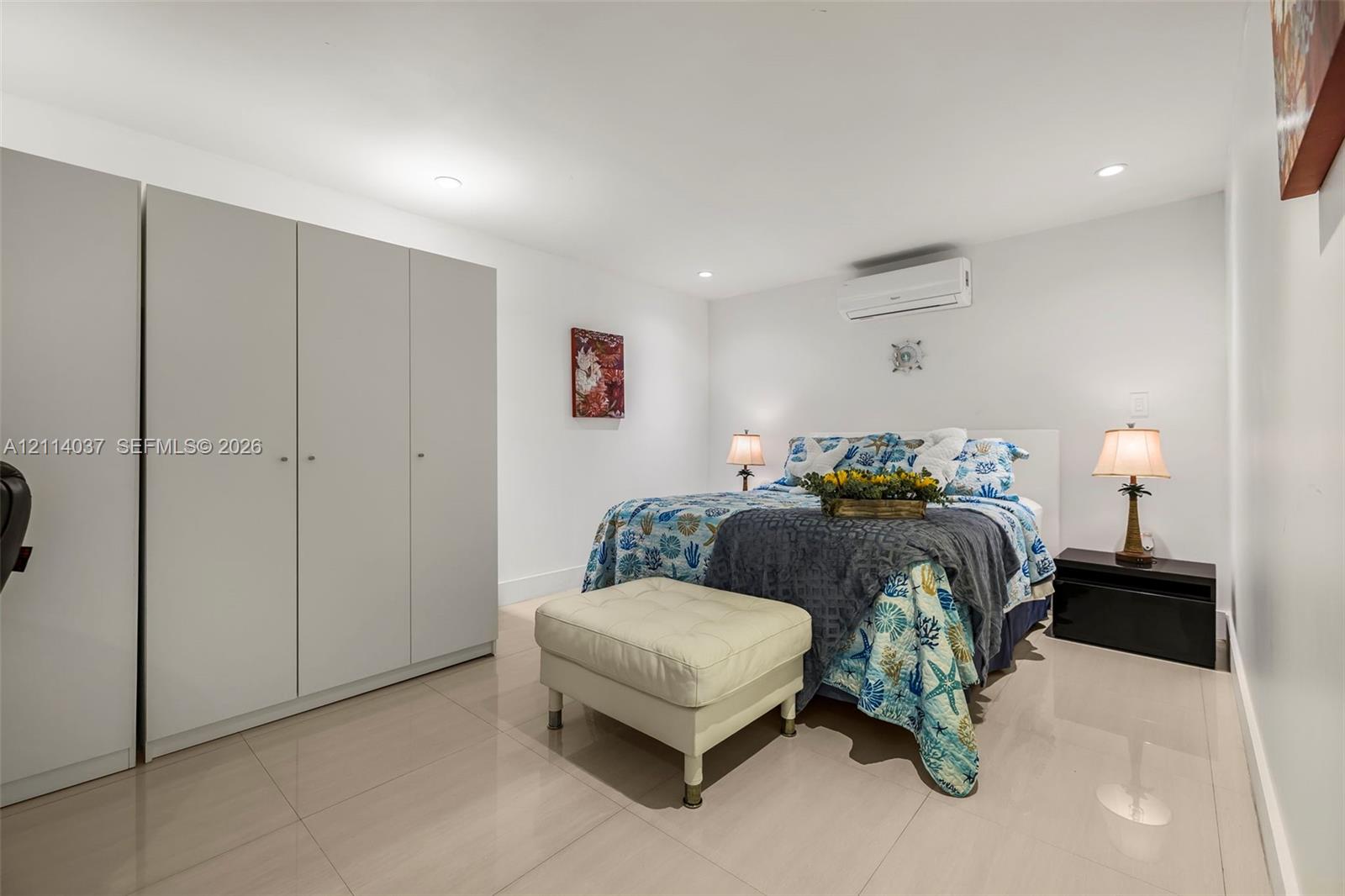Neutral-tone ceramic tile flooring, floor-to-ceiling built-in cabinetry, recessed ceiling lighting, and wall-mounted ductless climate control unit