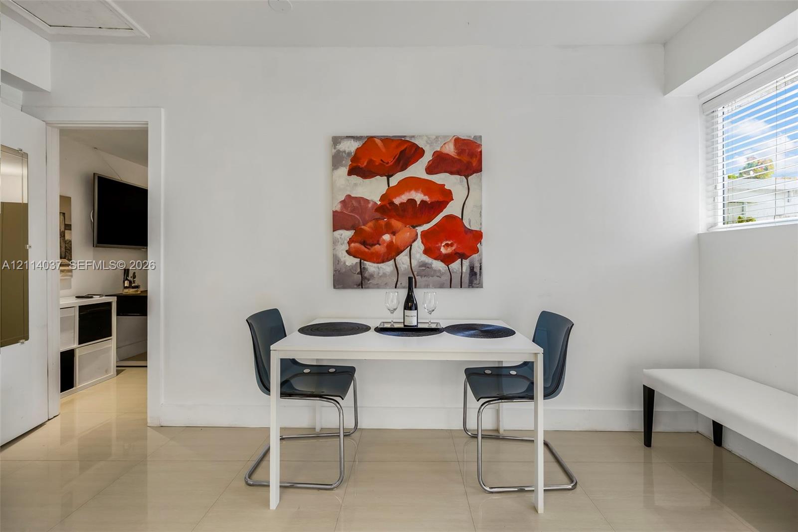 Neutral-toned tile flooring, minimalist white walls, and a horizontal window with fitted blinds