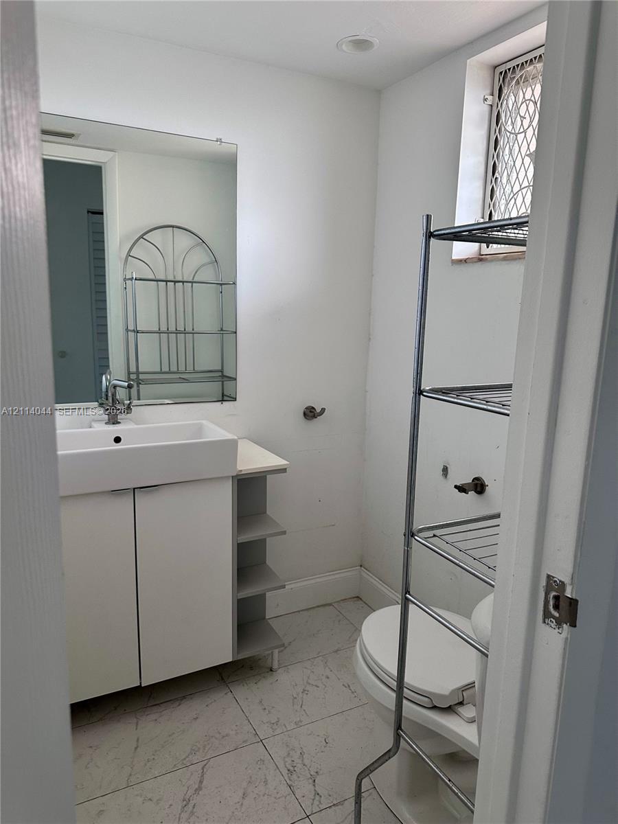 Bathroom featuring a rectangular vessel sink, vanity with built-in side shelving, large wall-mounted mirror, recessed ceiling lighting, and tile flooring
