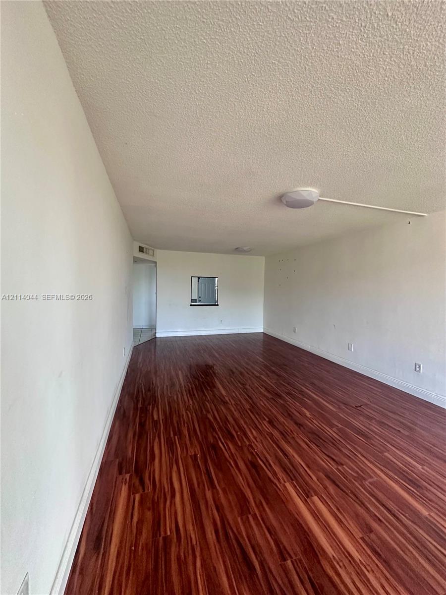 Interior space featuring wood-finish flooring, white walls, a flush-mount ceiling light fixture, and an interior pass-through window