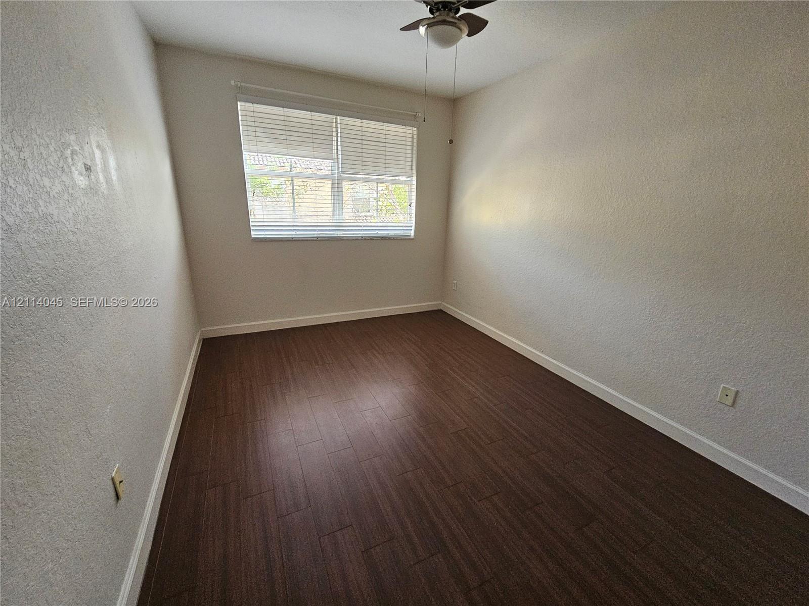 Wood-finish flooring, neutral wall finish, horizontal window blinds, and ceiling fan with integrated light fixture
