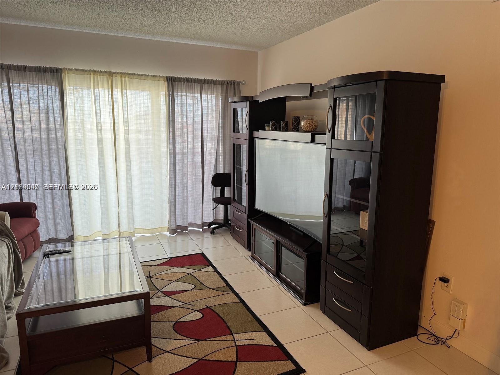 Living area featuring large-format tile flooring and floor-to-ceiling sliding glass doors