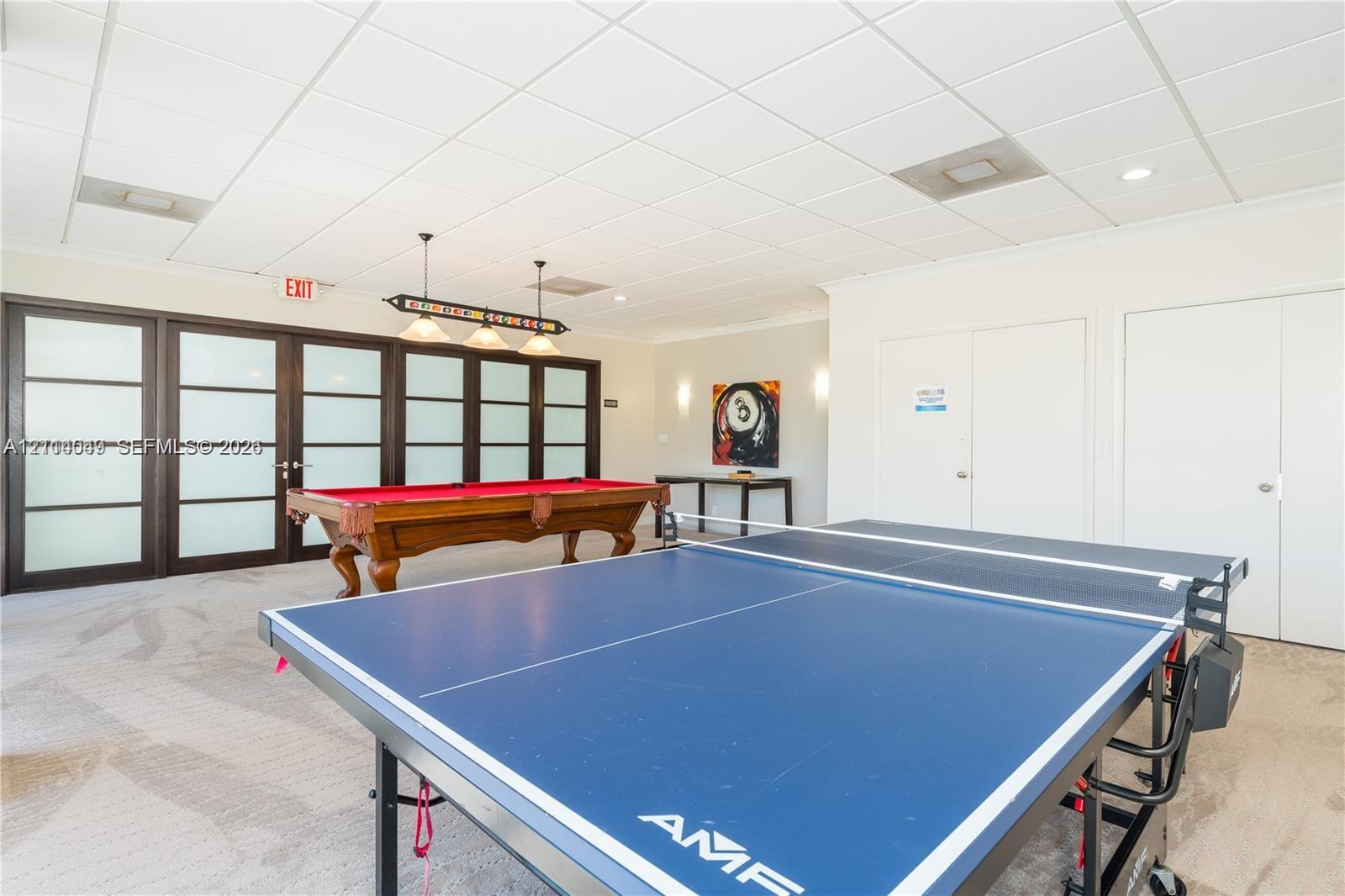 Expansive recreation room featuring a drop ceiling with recessed lighting, high-contrast dark-framed glass panel doors, and dual sets of built-in storage closets Expansive recreation room featuring a drop ceiling with recessed lighting, high-contrast dark-framed glass panel doors, and dual sets of built-in storage closets
