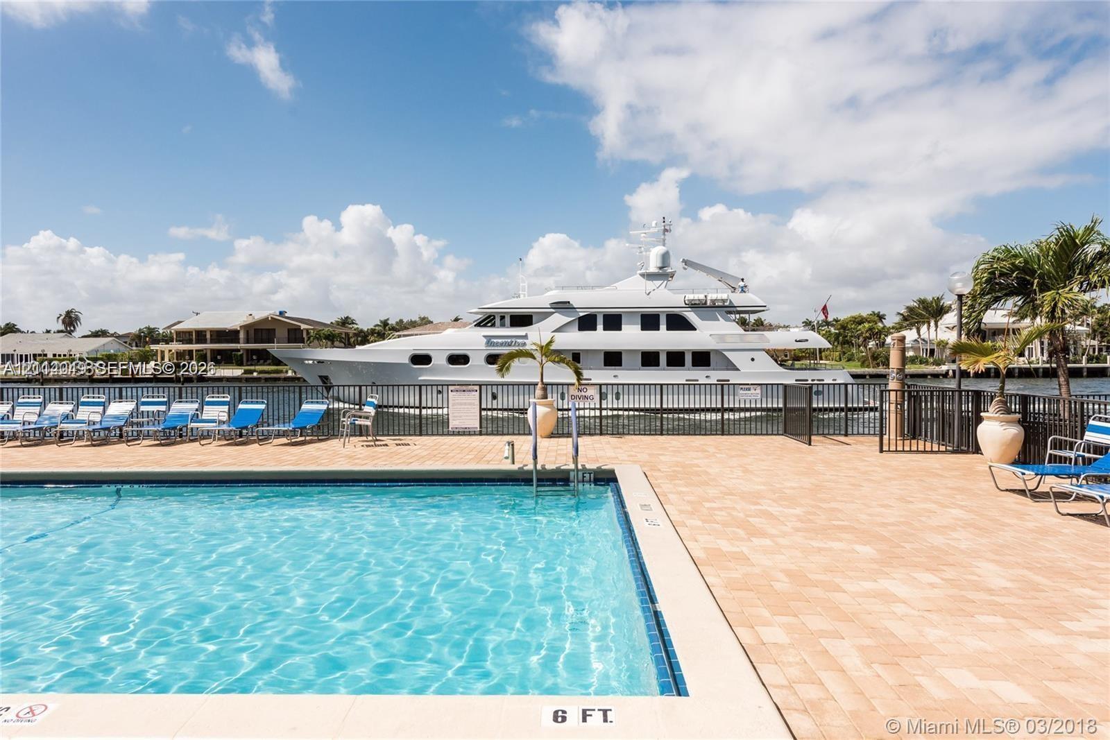 Swimming pool with a paved deck, black metal fencing, and water frontage Swimming pool with a paved deck, black metal fencing, and water frontage