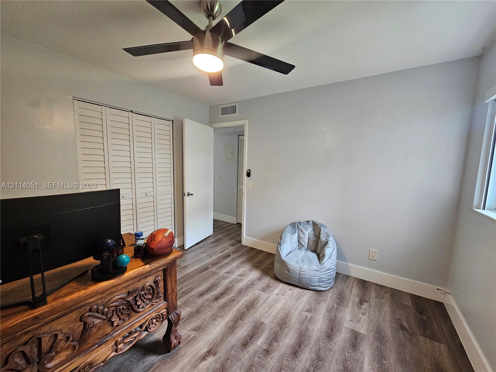 Wood-finish flooring, ceiling fan with integrated lighting, and louvered-door closet