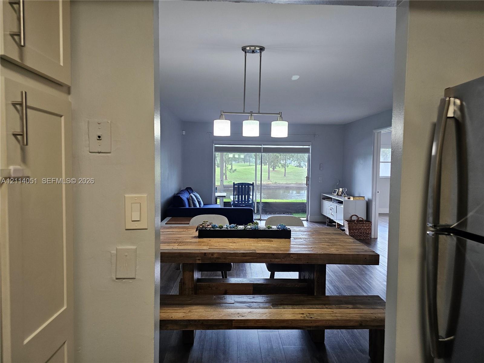 Neutral-toned cabinetry with satin nickel pulls, wood-finish flooring, and a three-light linear pendant fixture, punctuated by sliding glass doors Neutral-toned cabinetry with satin nickel pulls, wood-finish flooring, and a three-light linear pendant fixture, punctuated by sliding glass doors