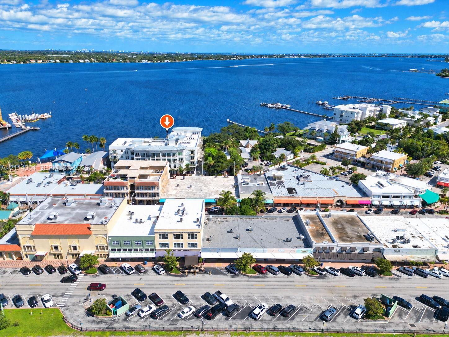 Aerial perspective of waterfront property featuring multi-story building architecture, direct proximity to open water, and localized street-level parking Aerial perspective of waterfront property featuring multi-story building architecture, direct proximity to open water, and localized street-level parking