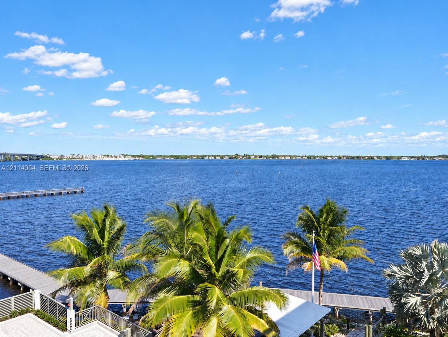 Waterfront property featuring a private dock, expansive deck, and mature palm trees Waterfront property featuring a private dock, expansive deck, and mature palm trees