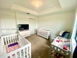 Tray ceiling featuring a central light fixture, wall-to-wall carpeting, and double-panel doors Tray ceiling featuring a central light fixture, wall-to-wall carpeting, and double-panel doors