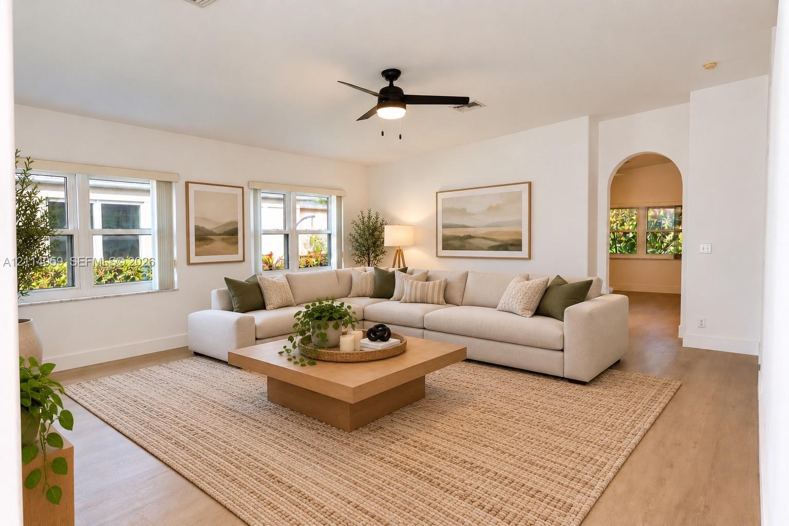 Spacious living area featuring wood-finish flooring, recessed lighting, a modern ceiling fan, and an architectural arched entryway