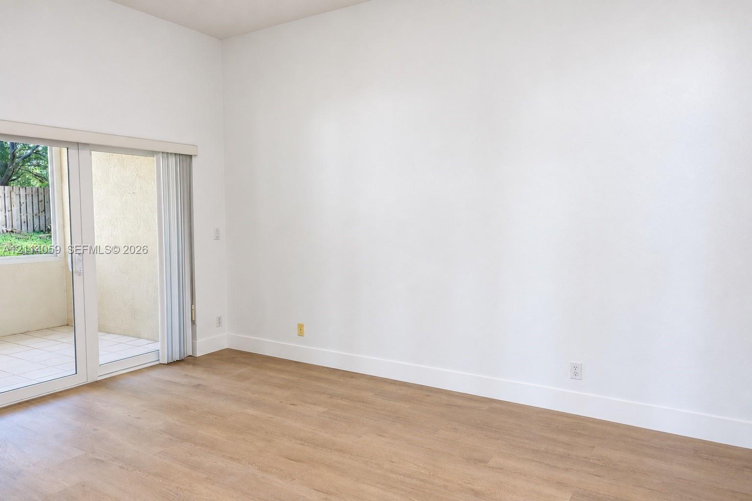 High ceilings, wood-finish flooring, and glass sliding doors with vertical blinds