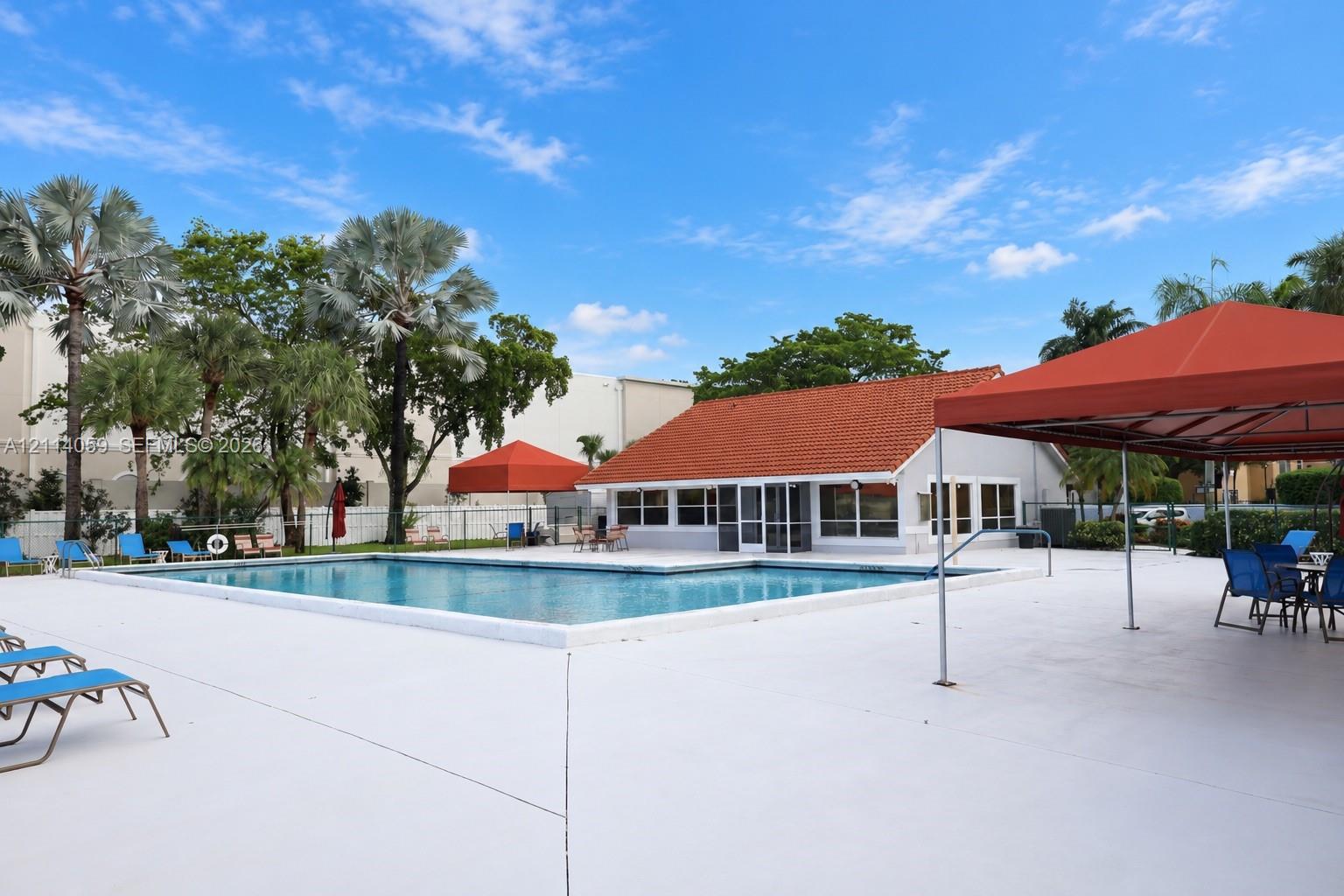 Swimming pool with a paved deck, terracotta-tiled roof structure, and perimeter landscaping