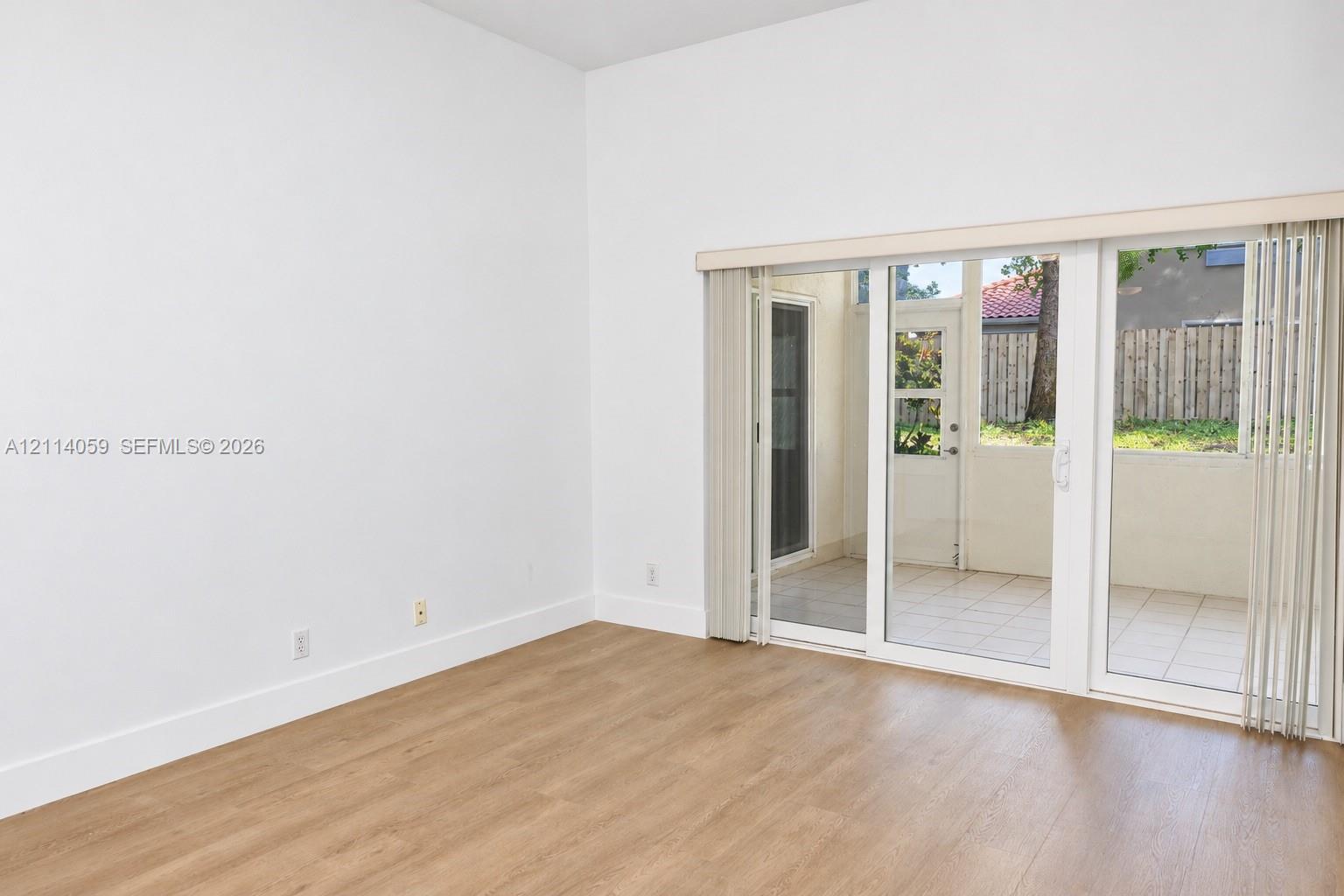 Room with wood-finish flooring and sliding glass doors opening to a tiled exterior patio