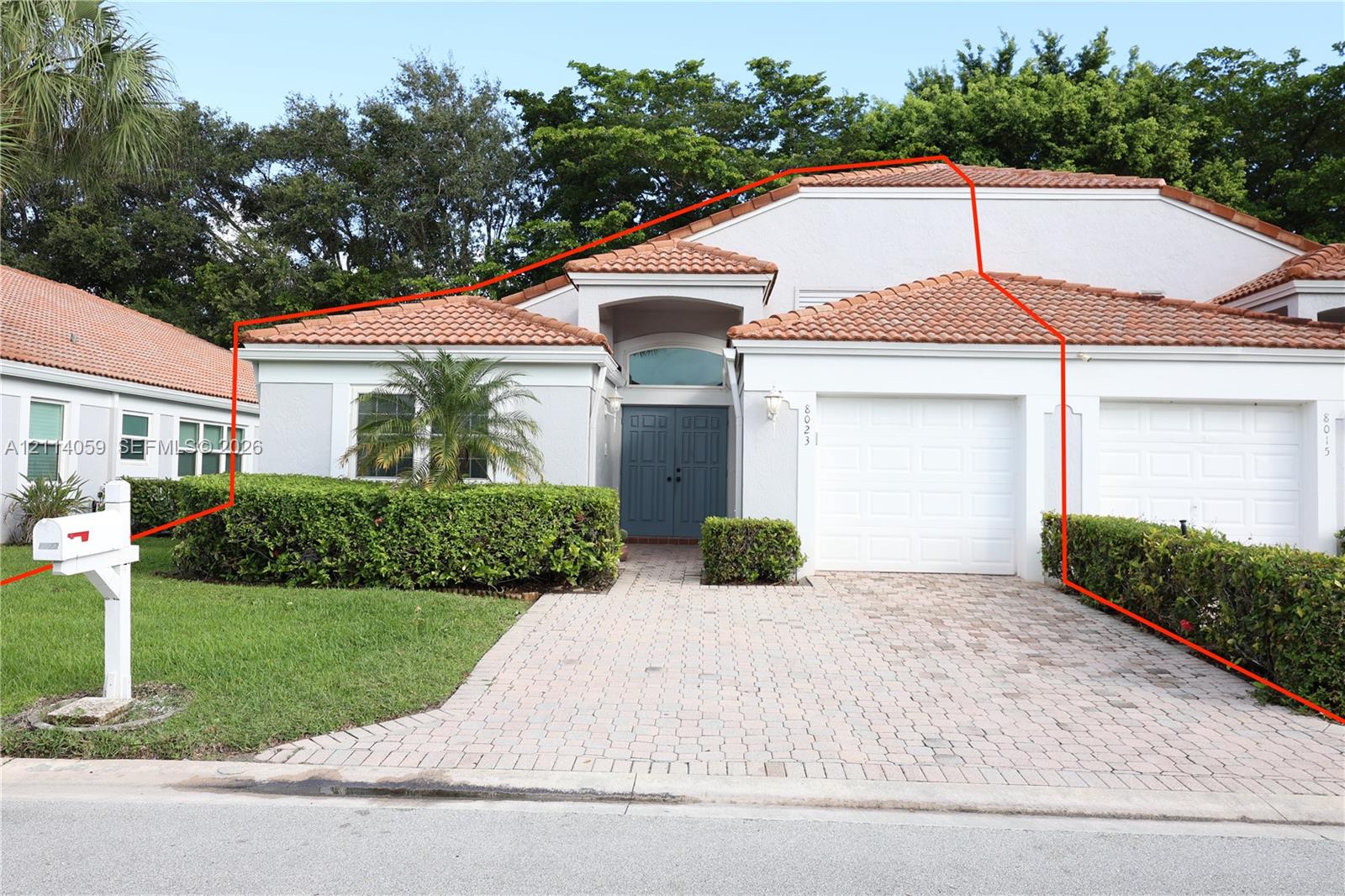 Stucco exterior featuring a clay tile roof, double-door entry with arched transom window, paved driveway, and attached two-car garage