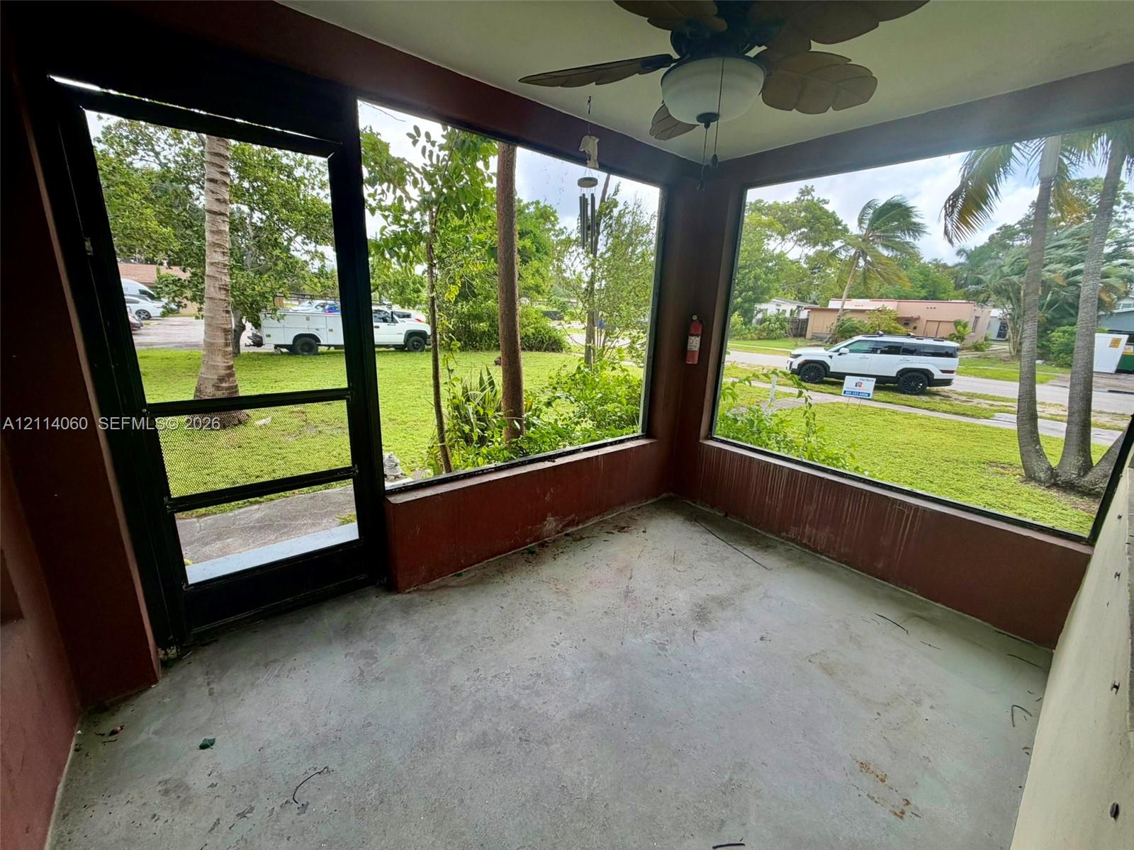 Enclosed patio featuring floor-to-ceiling windows, a screen door, and a ceiling-mounted light fixture with a fan