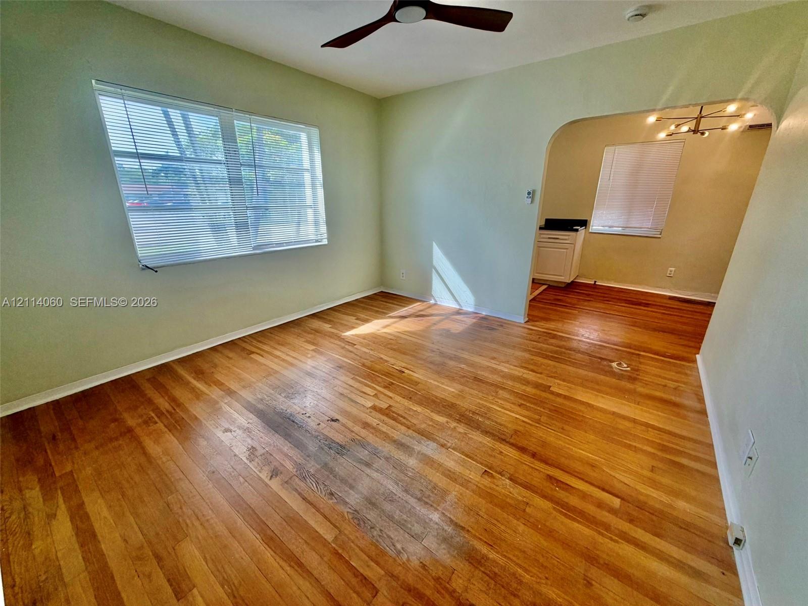 Hardwood flooring, arched entryway, ceiling fan, and window blinds