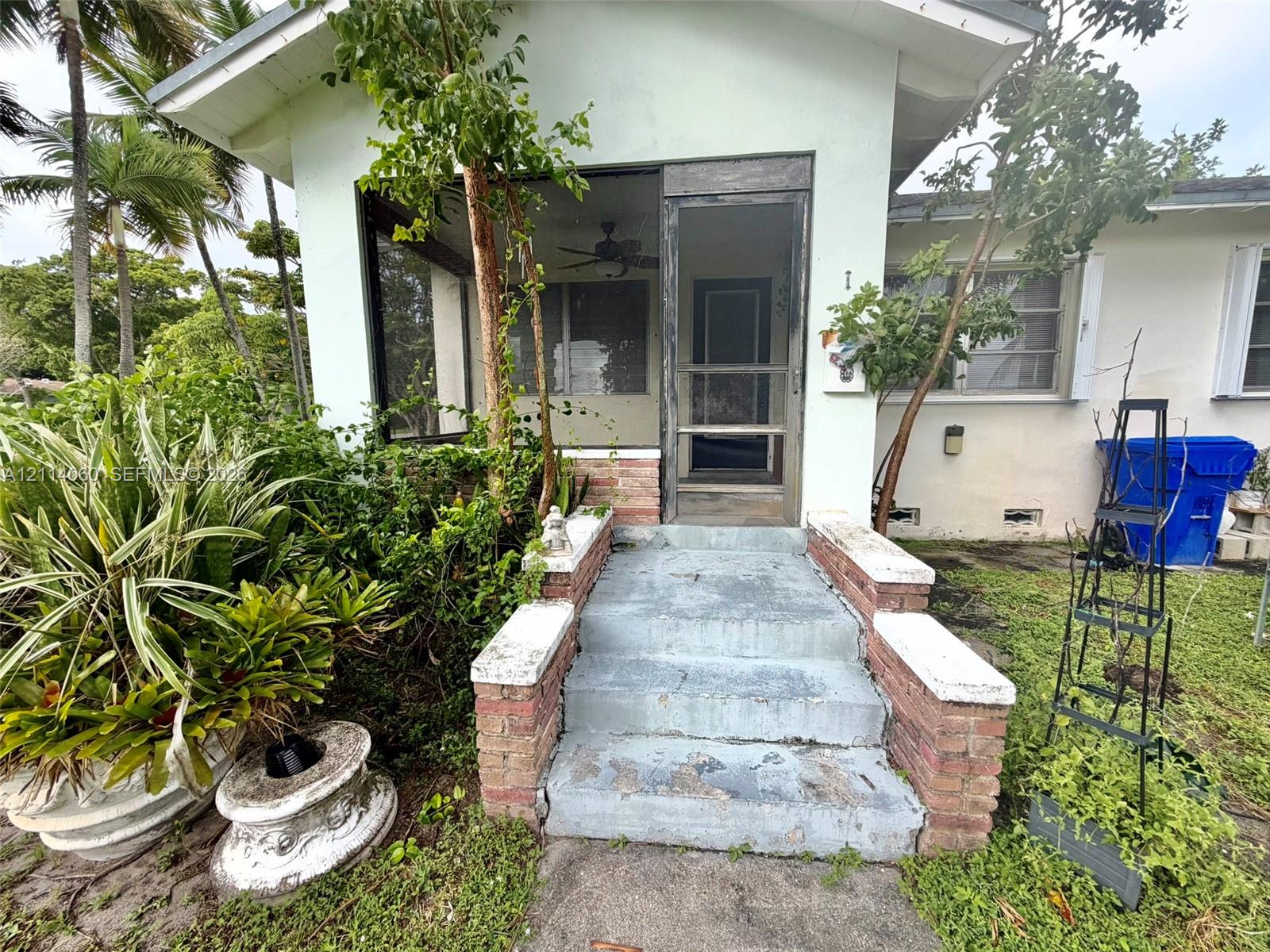 Screened porch entrance featuring concrete steps with decorative masonry brick pillars and a ceiling fan
